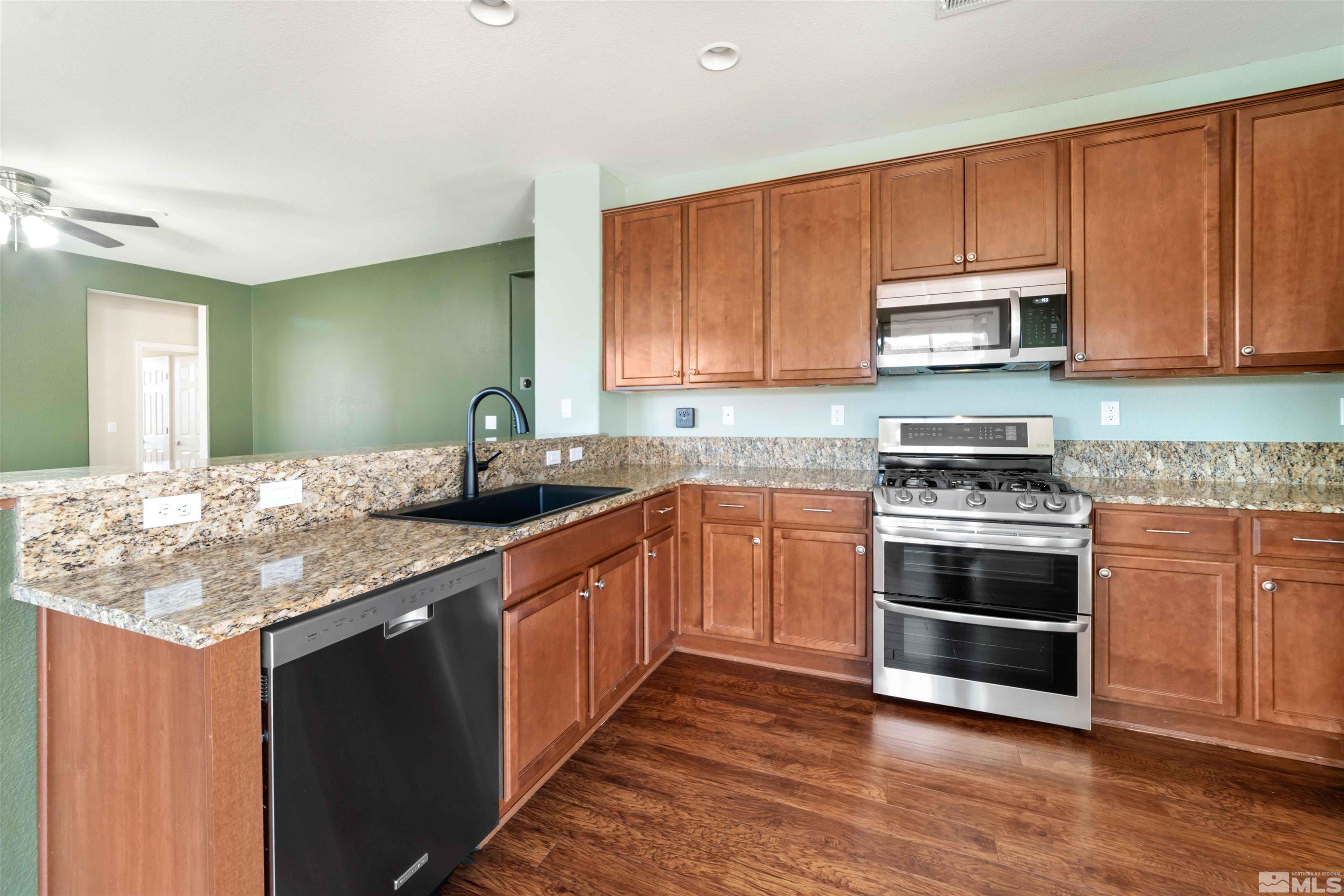 10790 Cedar Rock Drive Reno, NV 89521 - Photo 9 of 34 a kitchen with stainless steel appliances granite countertop a stove top oven a sink and dishwasher with wooden floor