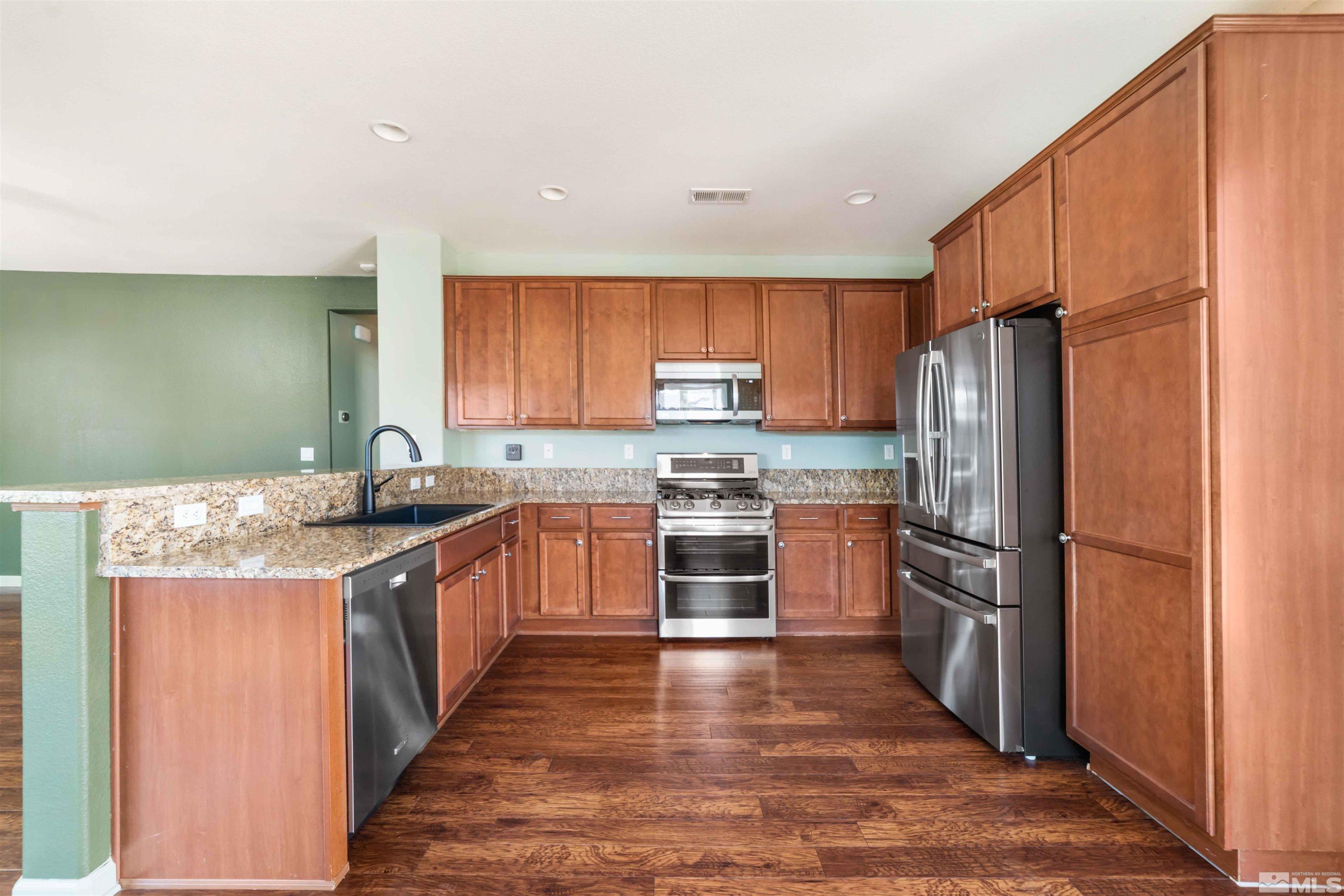 10790 Cedar Rock Drive Reno, NV 89521 - Photo 10 of 34 a kitchen with granite countertop stainless steel appliances and wooden cabinets