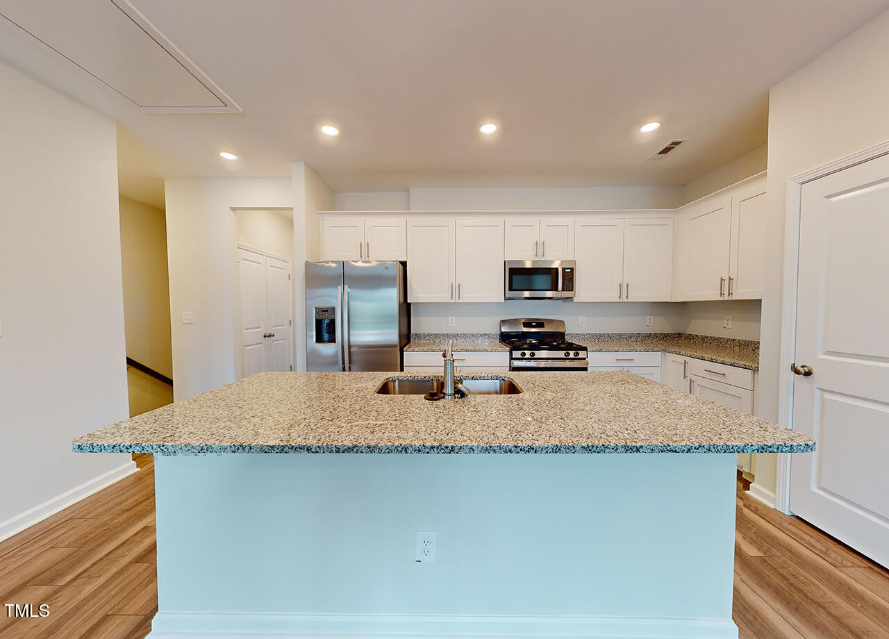 635 Cline Falls Drive, Unit HONEYSUCKLE Holly Springs, NC 27540 - Photo 2 of 23 a kitchen with stainless steel appliances granite countertop a sink refrigerator and microwave