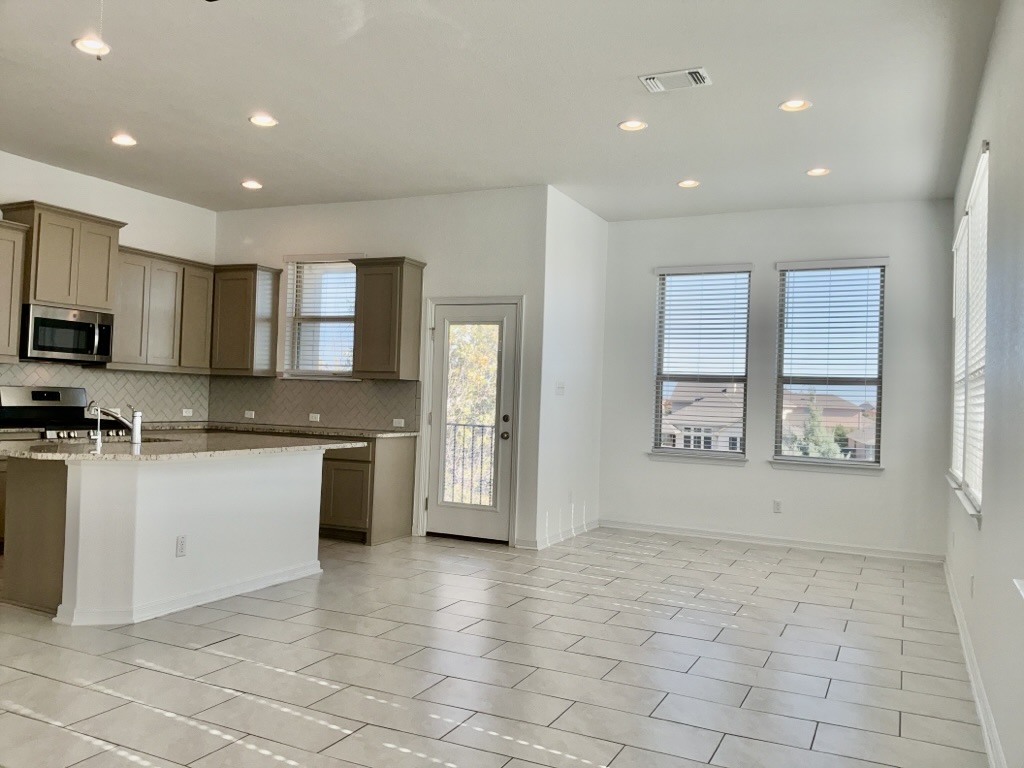 18005 Pomelo Lane, Unit A Pflugerville, TX 78660 - Photo 7 of 28 a large kitchen with a large counter top stainless steel appliances and cabinets