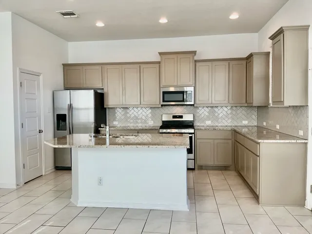 a kitchen with stainless steel appliances granite countertop a stove top oven a sink and a refrigerator