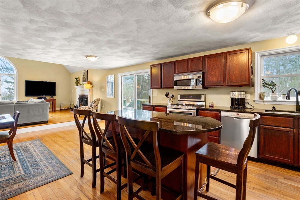28 Coleman Road Groveland, MA 01834 - Photo 3 of 37 a kitchen with stainless steel appliances granite countertop a stove a sink dishwasher a dining table and chairs with wooden floor