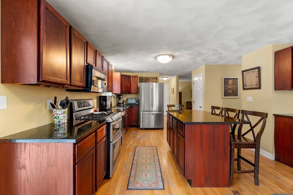 28 Coleman Road Groveland, MA 01834 - Photo 6 of 37 a kitchen with stainless steel appliances granite countertop a stove top oven a sink dishwasher a dining table and chairs with wooden floor