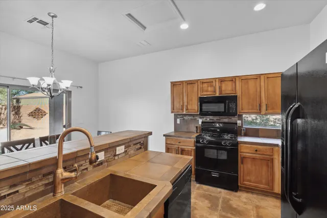 a kitchen with stainless steel appliances granite countertop a stove a sink dishwasher a refrigerator and a microwave with wooden floor