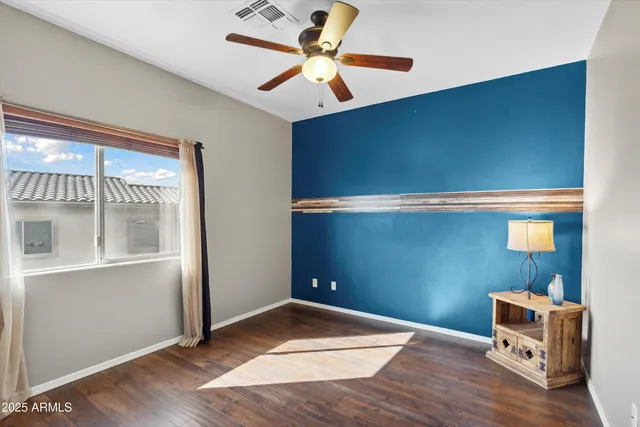 a view of room with wooden floor and a ceiling fan