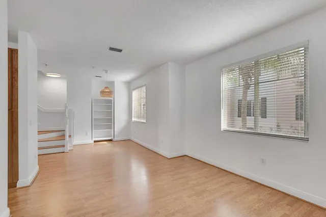 a view of empty room with wooden floor and fan