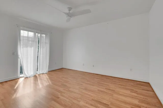 an empty room with wooden floor and windows