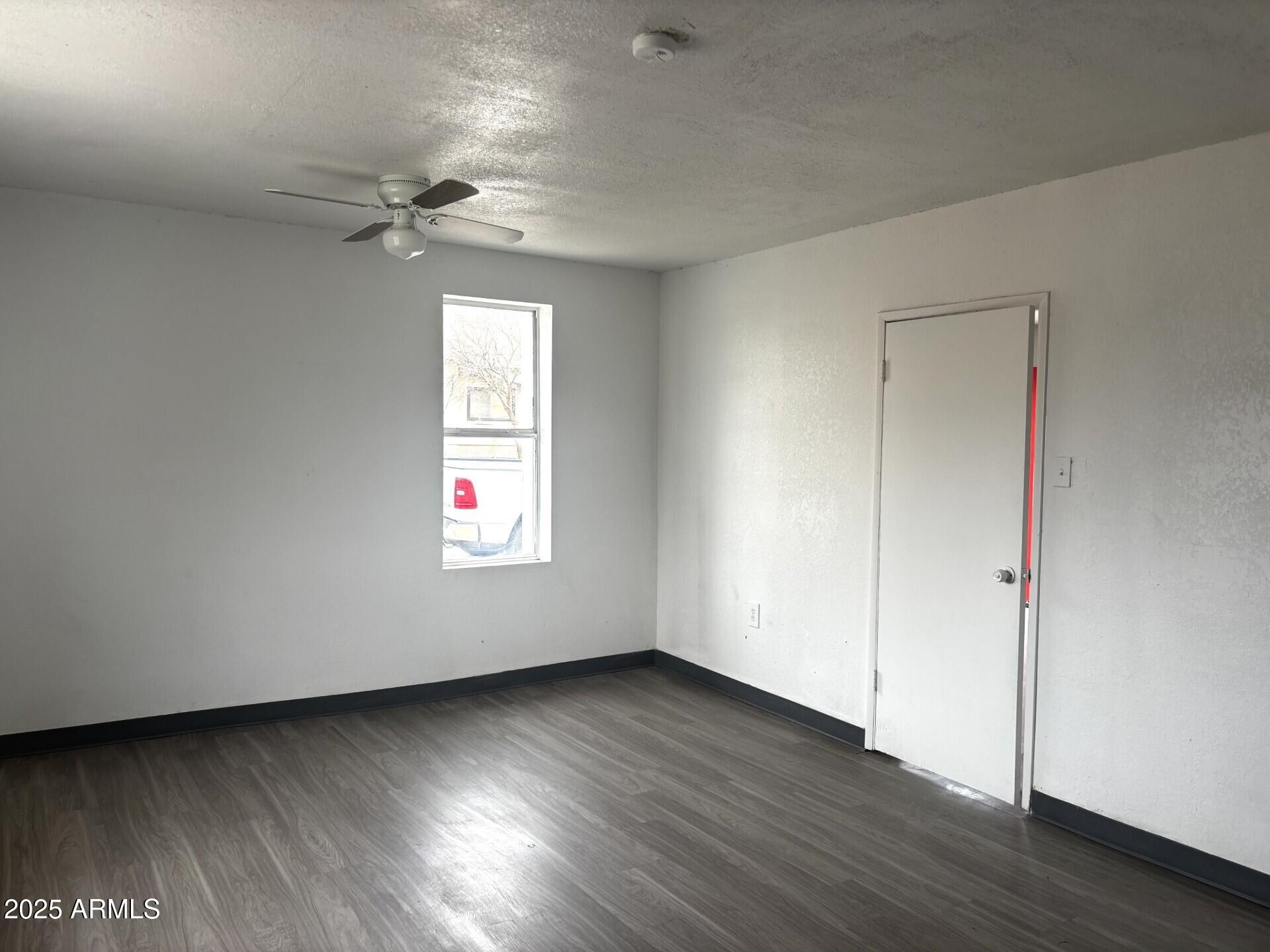 398 E Avenue Douglas, AZ 85607 - Photo 5 of 11 a view of an empty room with wooden floor and a window