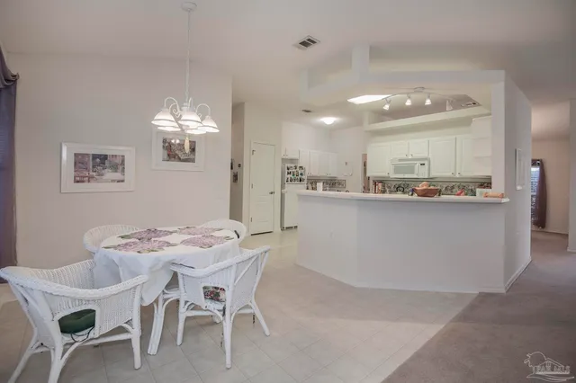 a dining hall with stainless steel appliances kitchen island granite countertop a table chairs and a refrigerator