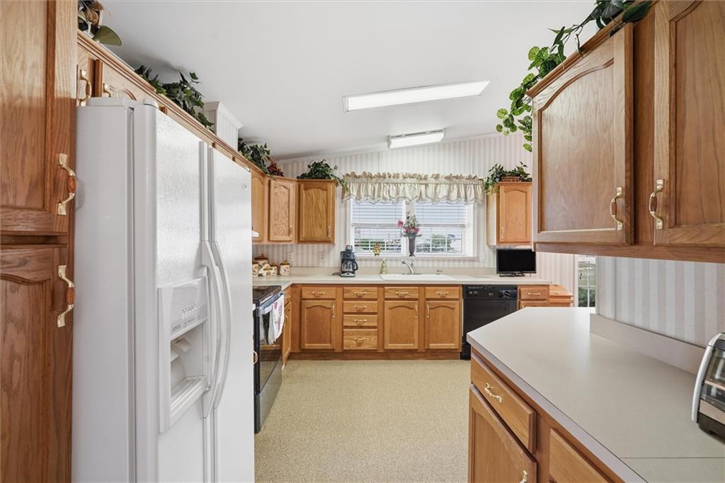2001 Pond Lane Elizabeth, PA 15037 - Photo 10 of 38 a kitchen with a sink a refrigerator a stove and white cabinets with wooden floor
