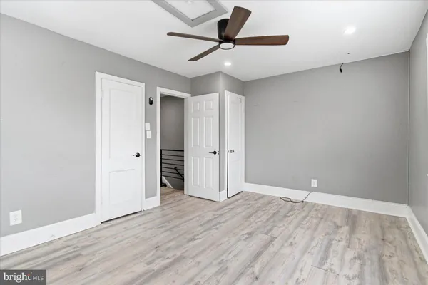 an empty room with wooden floor and a ceiling fan