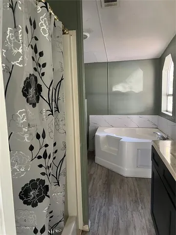 a bathroom with a sink and mirror with bathtub