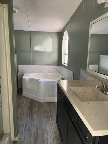 a bathroom with a granite countertop sink a mirror and shower