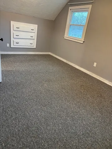 an empty room with a cabinet and a window