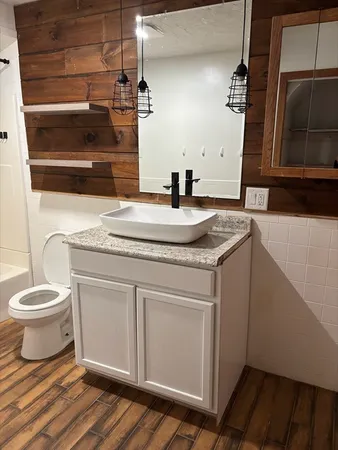 a bathroom with a granite countertop sink toilet and mirror
