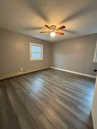 an empty room with wooden floor fan and window