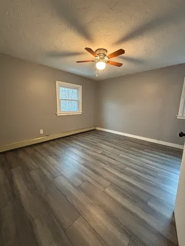 an empty room with wooden floor fan and window