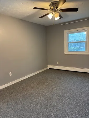 an empty room with a window and chandelier fan