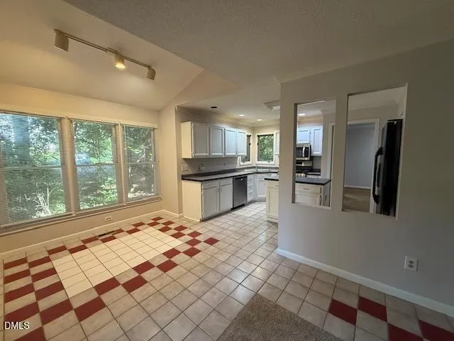 a large white kitchen with a stove a sink and a large window