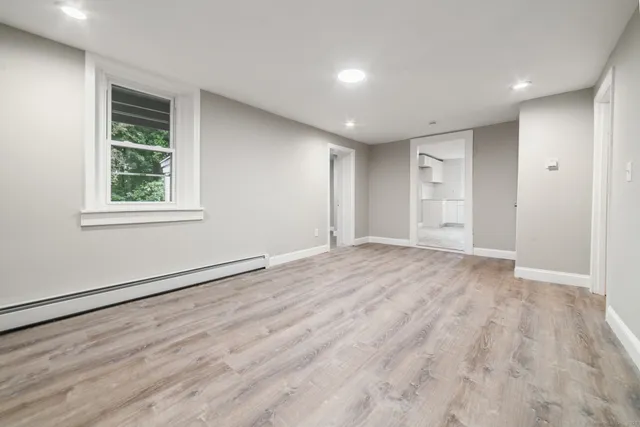 a view of empty room with wooden floor and fan