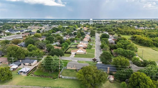 an aerial view of residential houses with outdoor space and trees