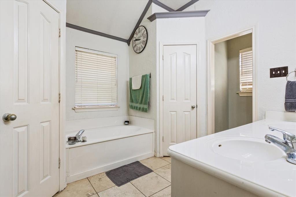 736 Tahoe Trail Hewitt, TX 76643 - Photo 19 of 30 Full bathroom with double vanity, light tile patterned floors, a bath, ornamental molding, and vaulted ceiling