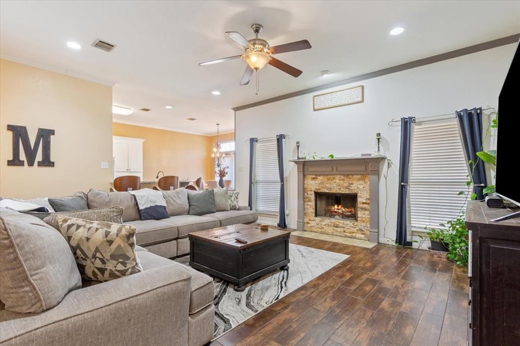 736 Tahoe Trail Hewitt, TX 76643 - Photo 9 of 30 Living area with ornamental molding, dark wood finished floors, a stone fireplace, recessed lighting, and a ceiling fan