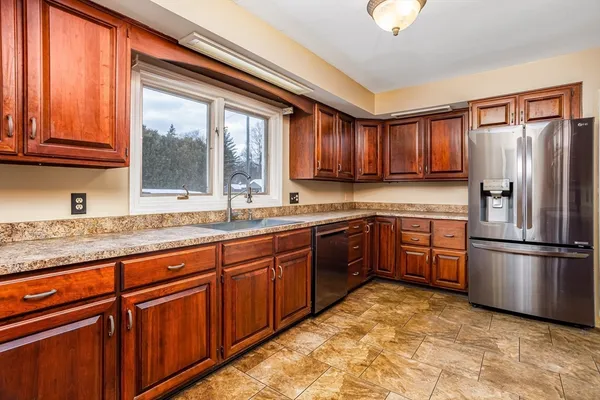 a kitchen with stainless steel appliances granite countertop a refrigerator and wooden cabinets