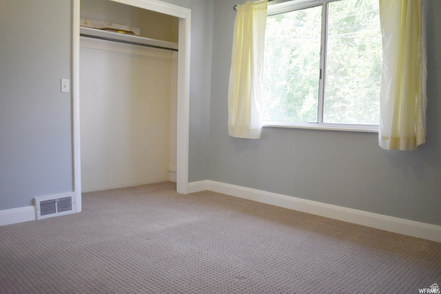 490 Averett Avenue Springville, UT 84663 - Photo 11 of 14 Carpeted room featuring a window with an exterior tree view, a built-in closet with shelving, light gray wall paint, and white baseboards