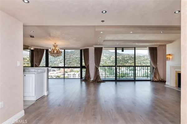 a view of an empty room with wooden floor and a fireplace
