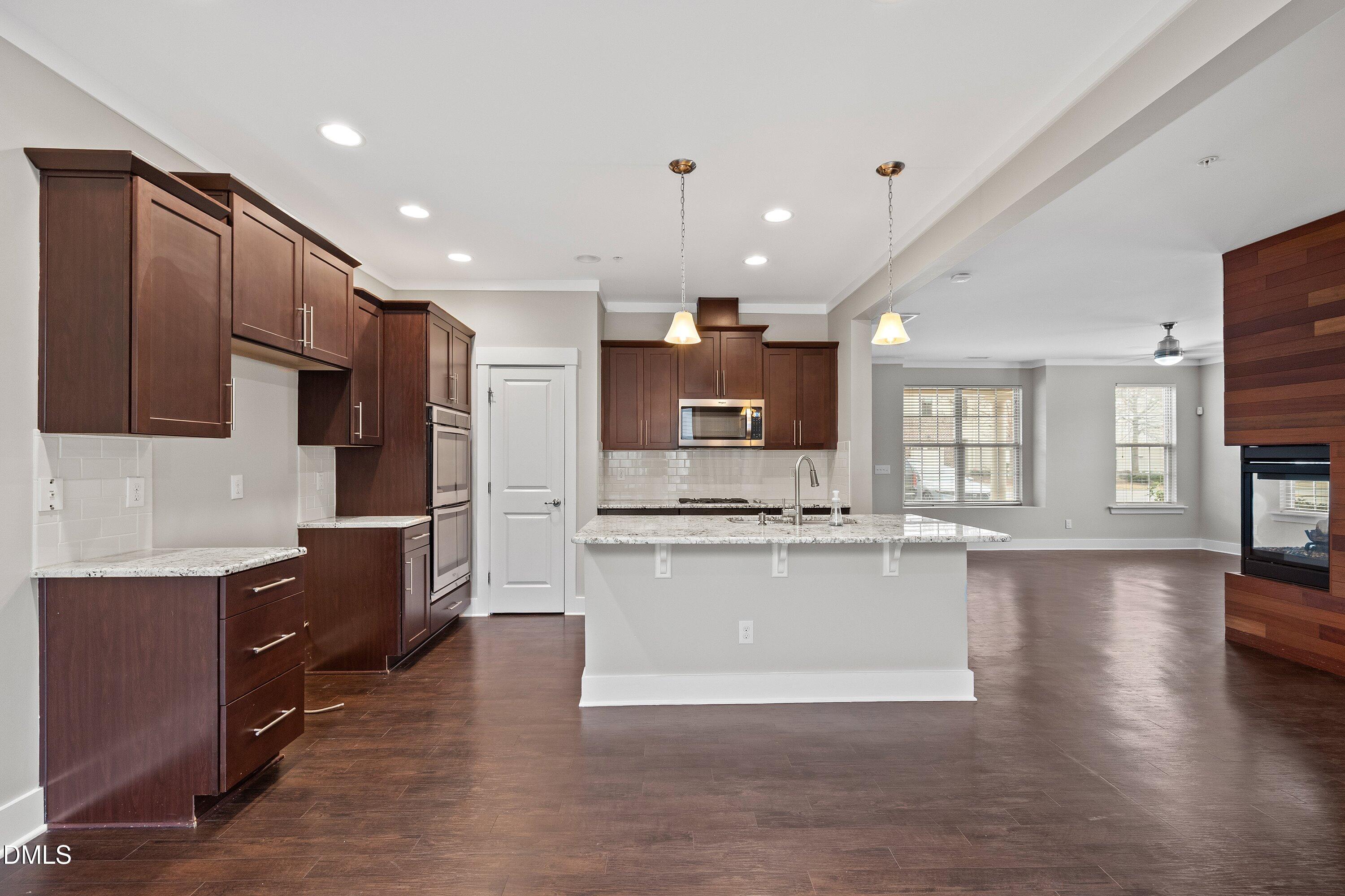 9903 Remedios Walk Raleigh, NC 27617 - Photo 16 of 53 a kitchen with stainless steel appliances kitchen island granite countertop a stove top oven a sink a refrigerator white cabinets and wooden floor