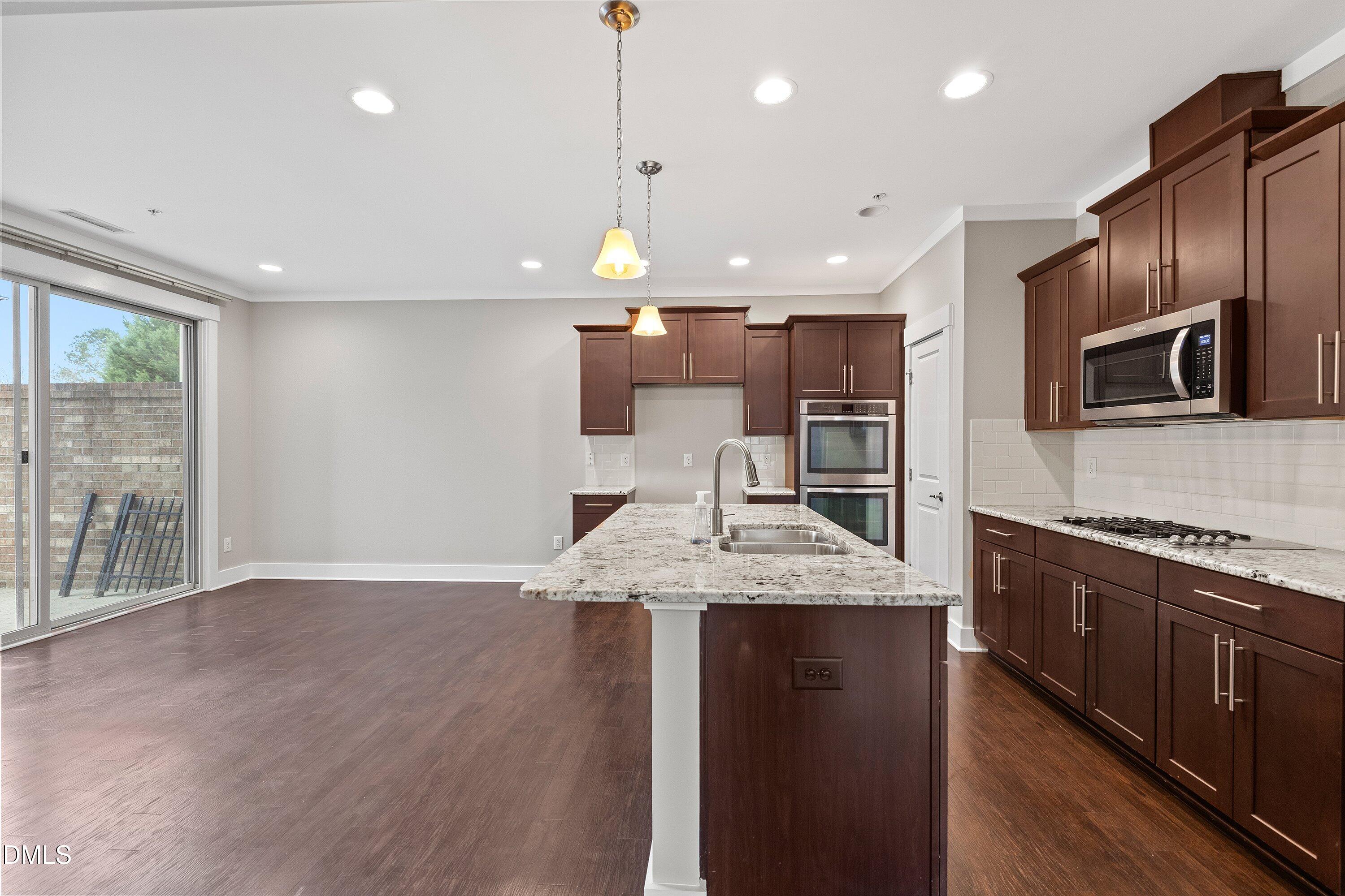 9903 Remedios Walk Raleigh, NC 27617 - Photo 19 of 53 a large kitchen with stainless steel appliances kitchen island granite countertop a stove a sink and a microwave