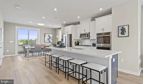 a kitchen with stainless steel appliances granite countertop a stove a refrigerator a kitchen island with a dining table and chairs