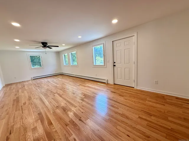 a view of empty room with wooden floor and fan