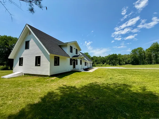 a front view of house with yard and trees in the background