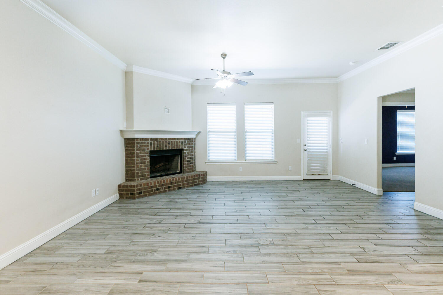 13801 Uvalde Avenue Lubbock, TX 79423 - Photo 16 of 46 an empty room with wooden floor fireplace and windows