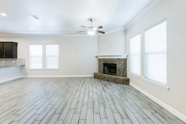 wooden floor fireplace and windows in an empty room
