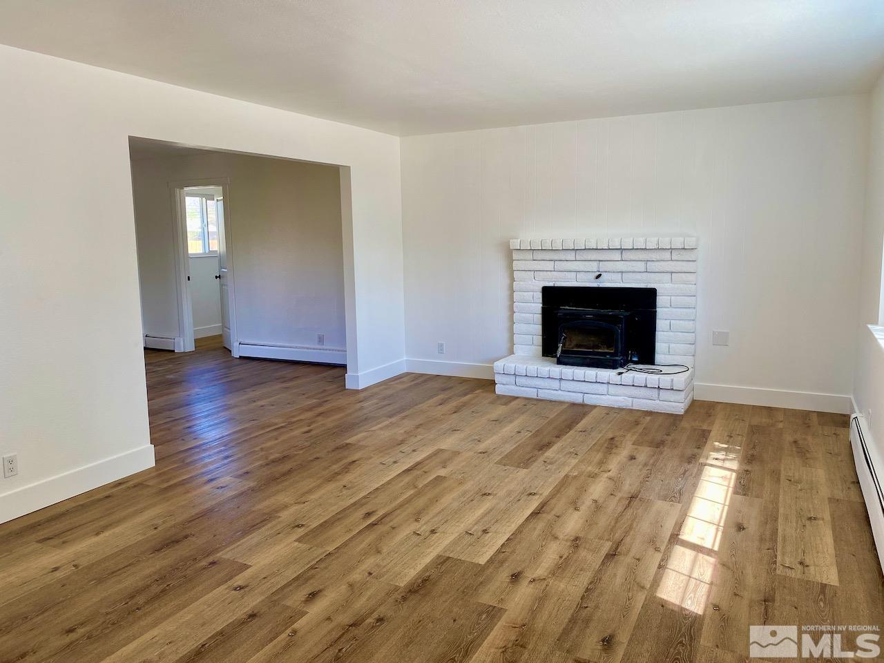 10775 Osage Road Reno, NV 89508 - Photo 6 of 22 an empty room with wooden floor fireplace and windows