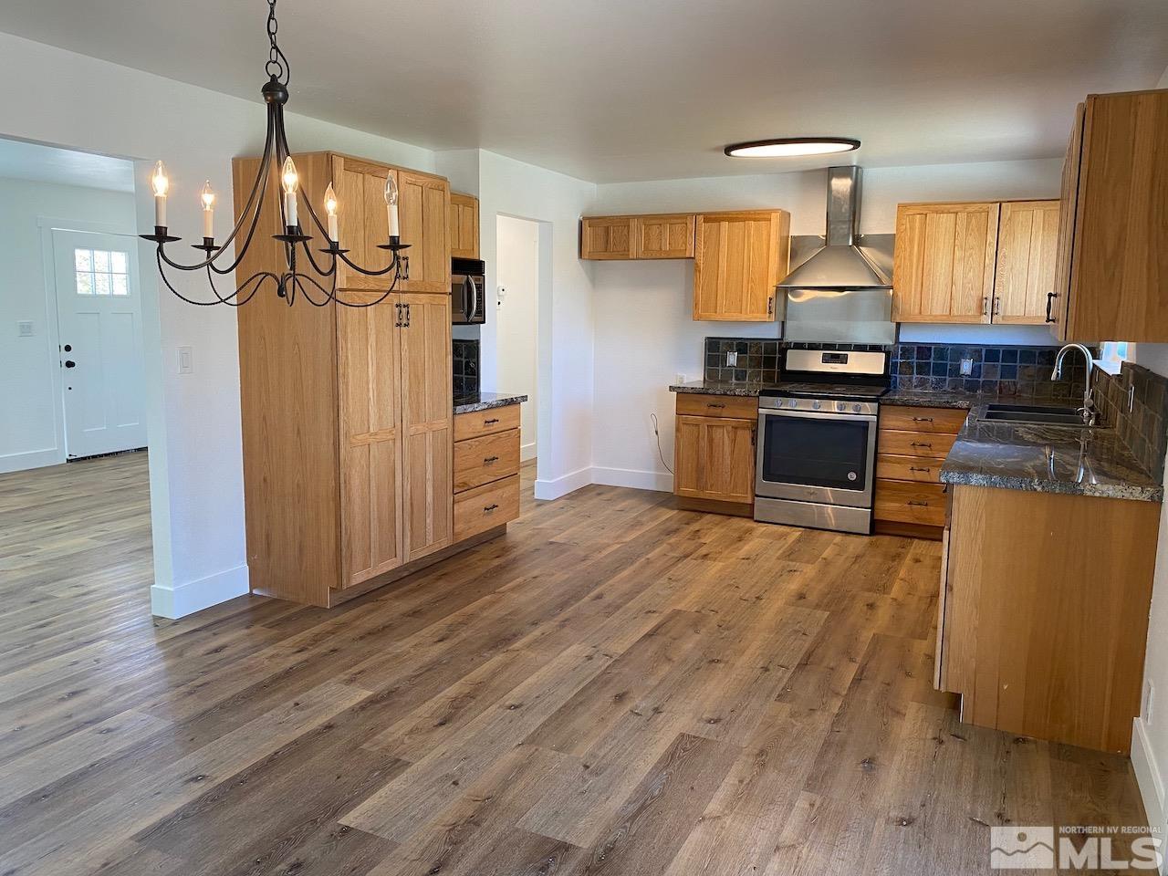 10775 Osage Road Reno, NV 89508 - Photo 7 of 22 a kitchen with stainless steel appliances granite countertop a refrigerator a sink dishwasher a stove and white countertops with wooden floor