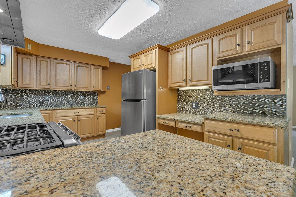 171 Dehaven Road Beaver Falls, PA 15010 - Photo 13 of 35 a kitchen with stainless steel appliances granite countertop a stove a sink and a microwave