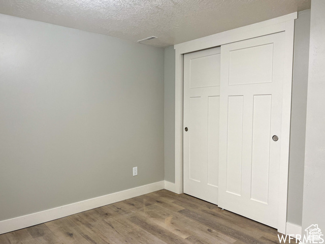 702 North 100 West Logan, UT 84321 - Photo 19 of 58 Unfurnished bedroom featuring baseboards, a closet, wood finished floors, and a textured ceiling