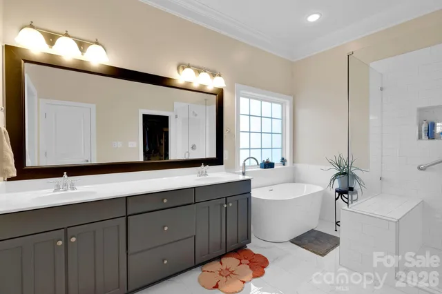 a bathroom with a double vanity sink a large mirror and bathtub