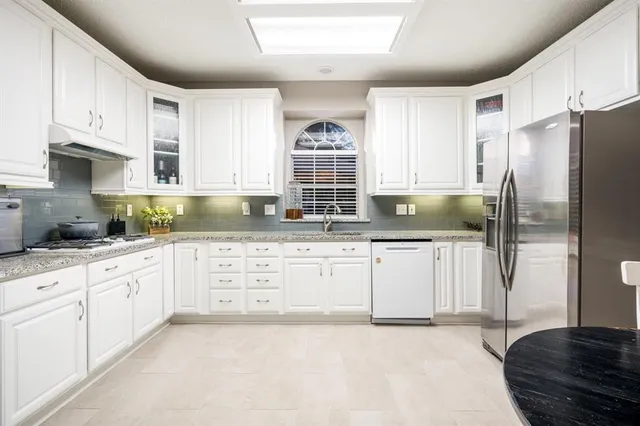 a kitchen with granite countertop a refrigerator sink and cabinets