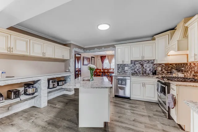 a kitchen with stainless steel appliances granite countertop a stove top oven a sink dishwasher and white cabinets with wooden floor