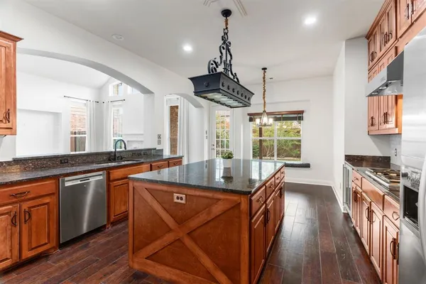 a kitchen with granite countertop a stove a sink and wooden floors