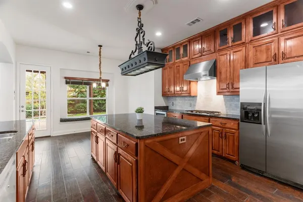 a kitchen with stainless steel appliances granite countertop a sink a stove and a wooden floors