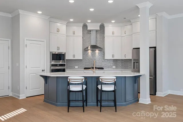 a kitchen with stainless steel appliances granite countertop a table chairs sink and cabinets
