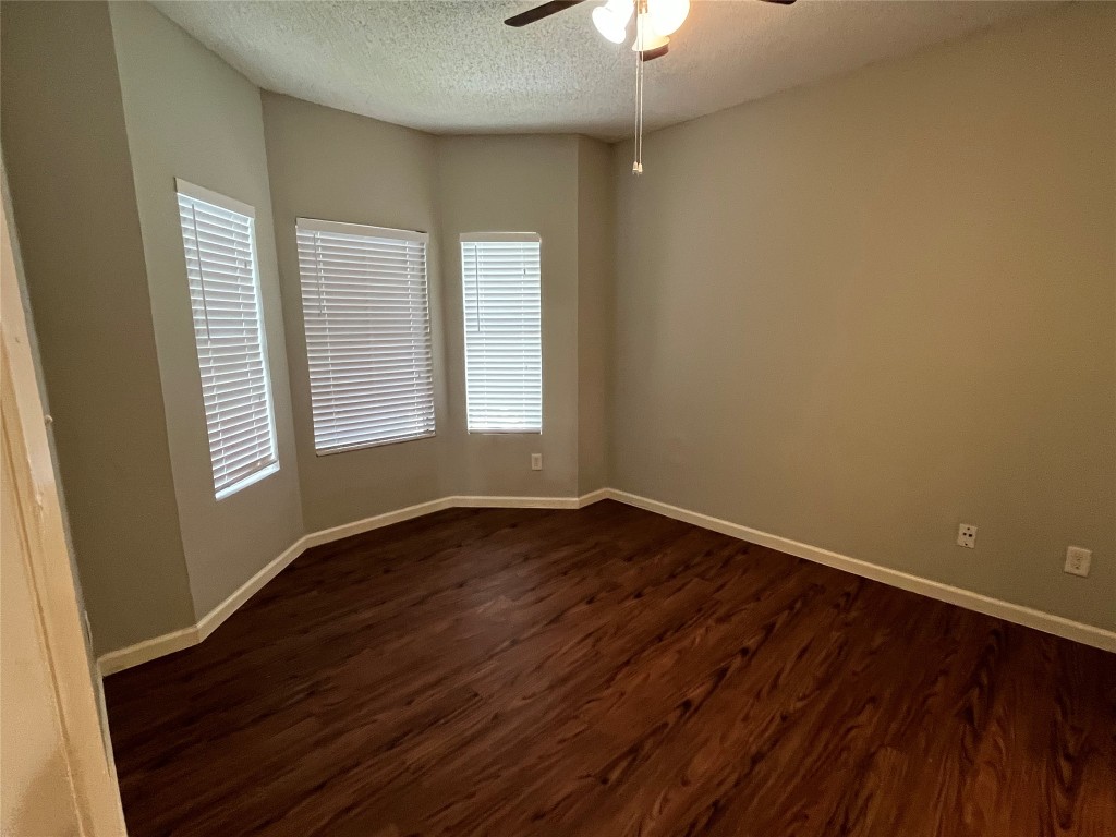 9502 Kempler Drive, Unit B Austin, TX 78748 - Photo 12 of 18 Spare room featuring dark wood-style flooring, a textured ceiling, and a ceiling fan