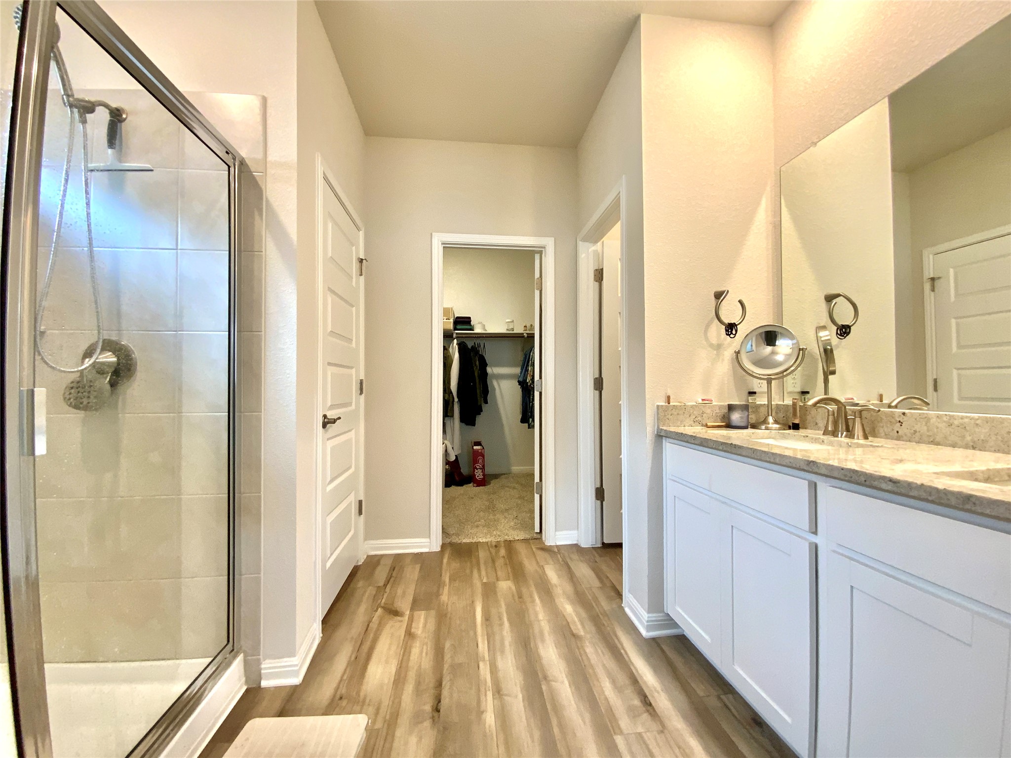 246 El Capitan Loop Dripping Springs, TX 78620 - Photo 21 of 37 Full bath featuring a stall shower, vanity, light wood-style floors, and a walk in closet