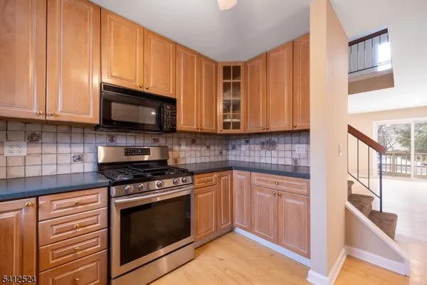 a kitchen with stainless steel appliances granite countertop wooden cabinets a stove a sink and a microwave